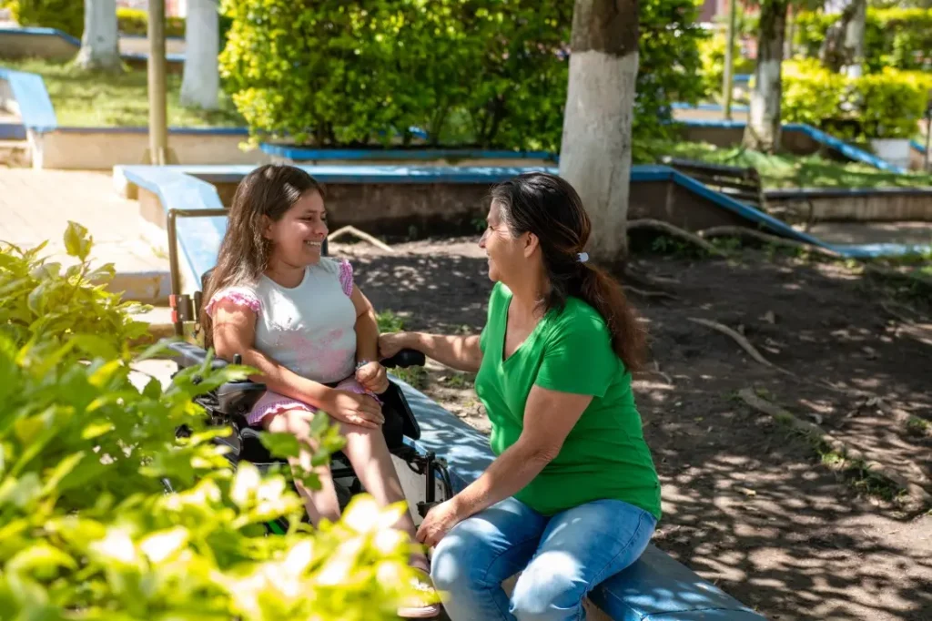 Disabled girl in wheelchair smiling with support worker