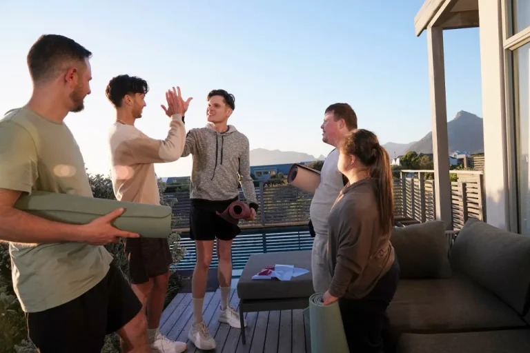 Group of diverse friends holding exercise mats and high fiving
